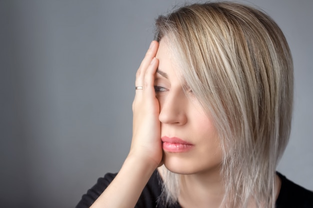 Une femme triste avec un anneau à la main appuie sa main sur le battement