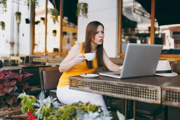 Femme triste bouleversée dans un café de rue en plein air assis à table travaillant sur un ordinateur portable moderne, déranger le problème dans le restaurant pendant le temps libre