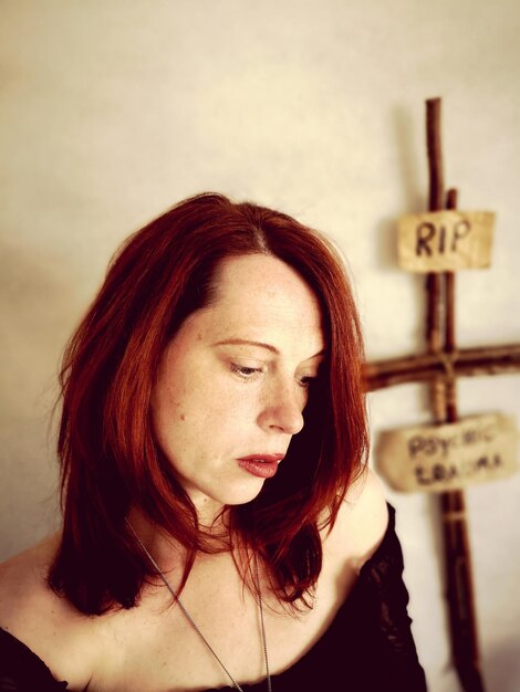 Photo une femme triste debout avec une croix et un texte accrochés au mur.