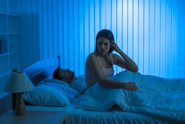 La femme triste est assise près d'un homme dans le lit. la nuit