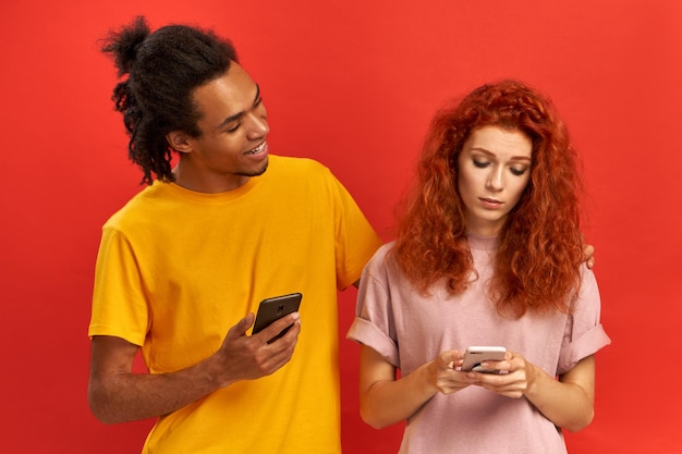 Une femme triste et frustrée tient un téléphone portable, perplexe de recevoir une facture par e-mail, recherche des fichiers multimédias à télécharger, un ami amical à la peau sombre embrasse et essaie de calmer tout va bien