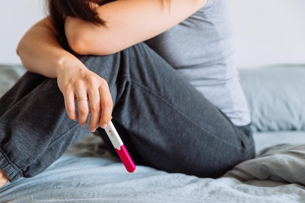 Femme triste sur le lit avec un test de grossesse négatif