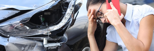 Femme triste parlant au téléphone portable près du concept de conduite de femme de voiture cassée