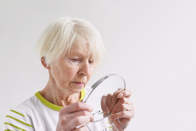 femme triste senior se regardant dans le miroir concept de soins de la peau de temps d'âge