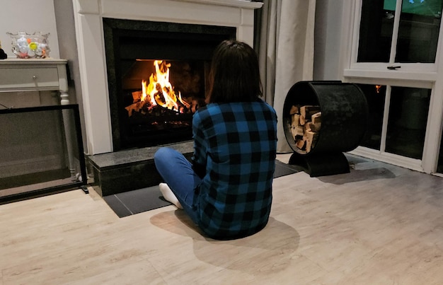 Une femme triste et solitaire regardant le feu dans la cheminée du salon.