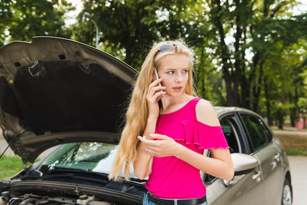 Femme triste en stress avec téléphone portable près de voiture