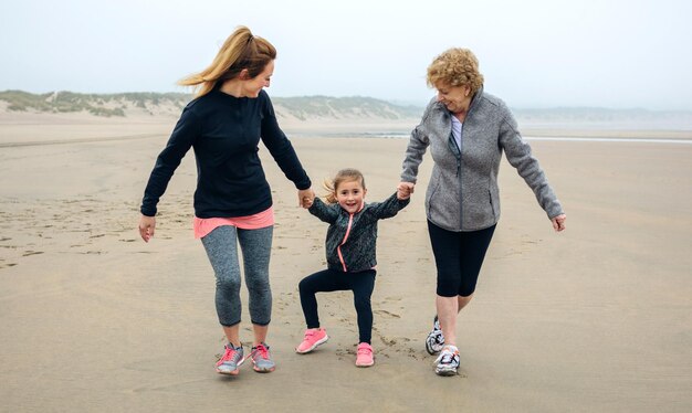 Femme de trois générations courant sur la plage en automne