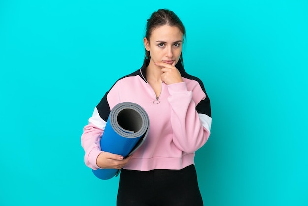 Femme ukrainienne sportive allant à des cours de yoga tout en tenant un tapis en pensant
