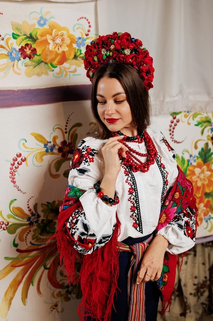 Femme ukrainienne en vêtements ethniques traditionnels et couronne rouge florale sur fond de poêle décoré dans la hutte Robe brodée nationale ukrainienne appelez vyshyvanka Priez pour l'Ukraine