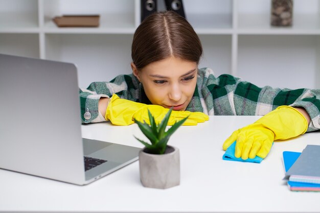 Femme en uniforme avec des fournitures de nettoyage au bureau.