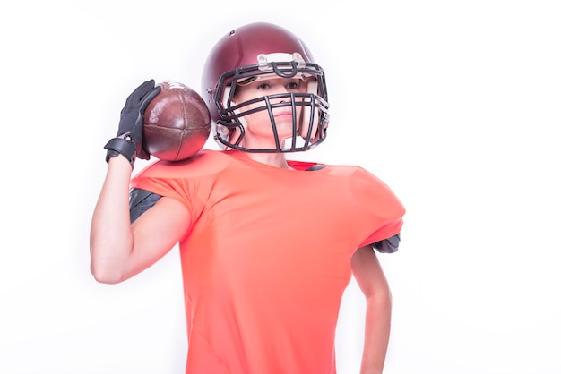 Photo femme en uniforme d'un joueur de l'équipe de football américain posant avec un ballon sur fond blanc. notion de sport. technique mixte