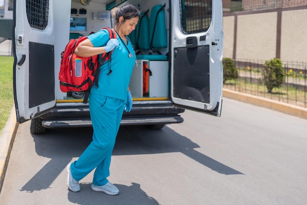 Femme en uniforme avec un sac de premiers soins à côté d'une ambulance