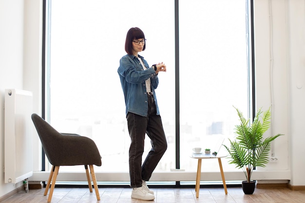 Femme utilisant l'application sur smartwatch pendant le travail au bureau