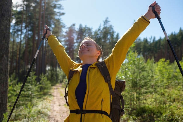 Femme utilisant des bâtons de trekking spéciaux marchant dans la forêt