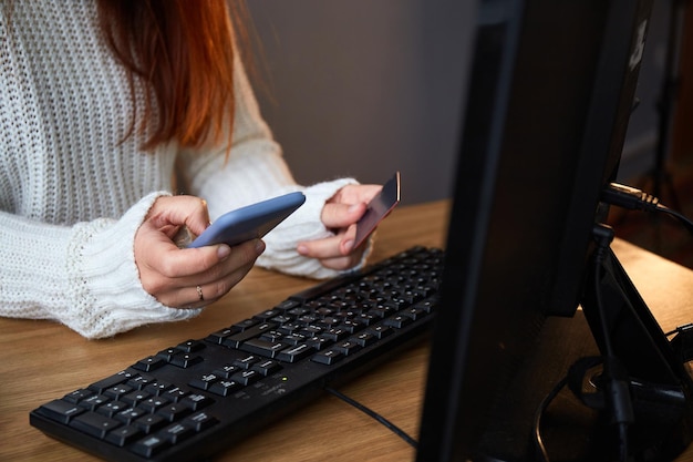Femme utilisant une carte de crédit et un téléphone pour faire des achats en ligne