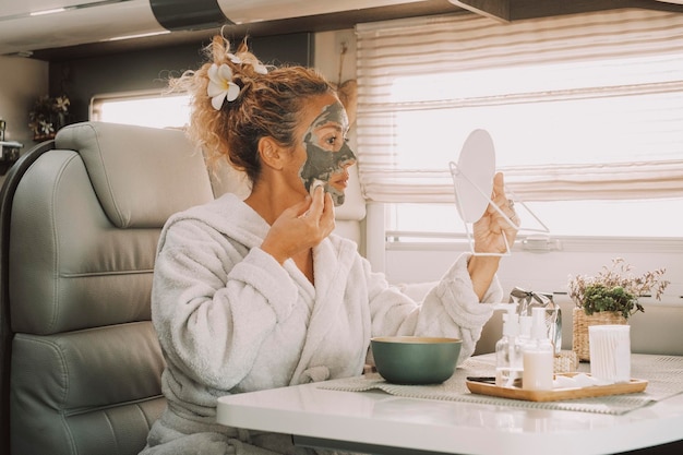 Une femme utilisant une crème de beauté sur le visage pour arrêter de vieillir et éliminer les rides Les femmes utilisent des produits naturels sur sa peau à l'intérieur d'un camping-car dans un mode de vie alternatif hors réseau