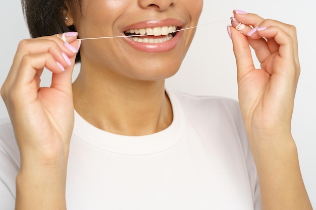 Femme utilisant du fil dentaire pour nettoyer les dents après la nourriture