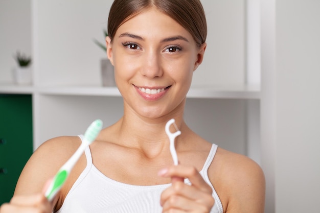 Femme utilisant du fil dentaire pour nettoyer ses dents