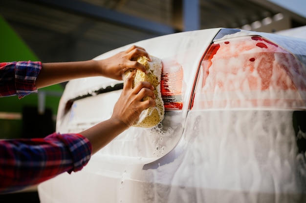 Femme Utilisant Une éponge Et De La Mousse, Station De Lavage Automatique Des Mains. Industrie Ou Entreprise De Lavage De Voitures. La Personne De Sexe Féminin Nettoie Son Véhicule De La Saleté à L'extérieur