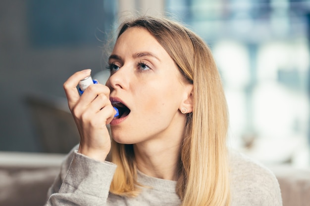 femme utilisant un inhalateur alors qu'elle souffre d'asthme à la maison