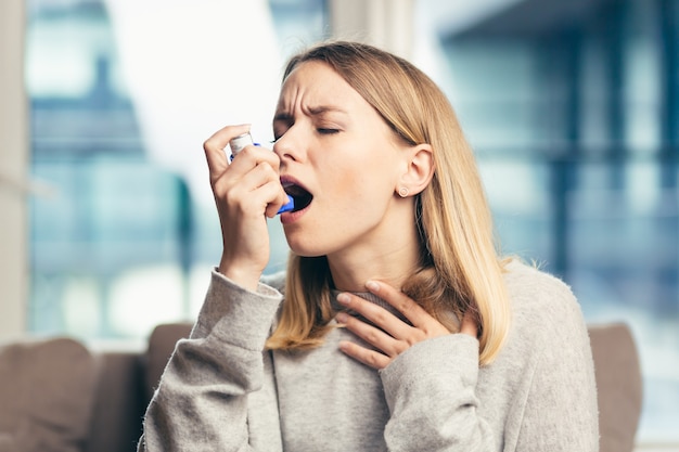 femme utilisant un inhalateur alors qu'elle souffre d'asthme à la maison