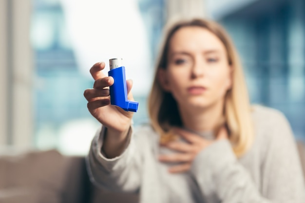 femme utilisant un inhalateur alors qu'elle souffre d'asthme à la maison