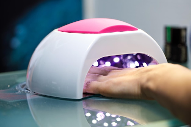 Femme utilisant une lampe UV pour sécher les ongles avec la méthode du gel.