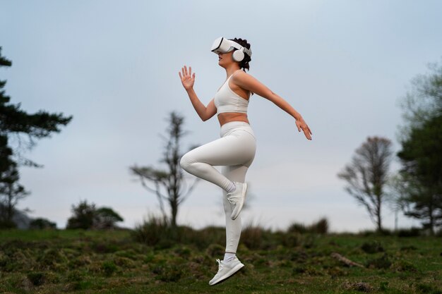 Photo femme utilisant des lunettes vr pour faire de l'exercice à l'extérieur dans la nature