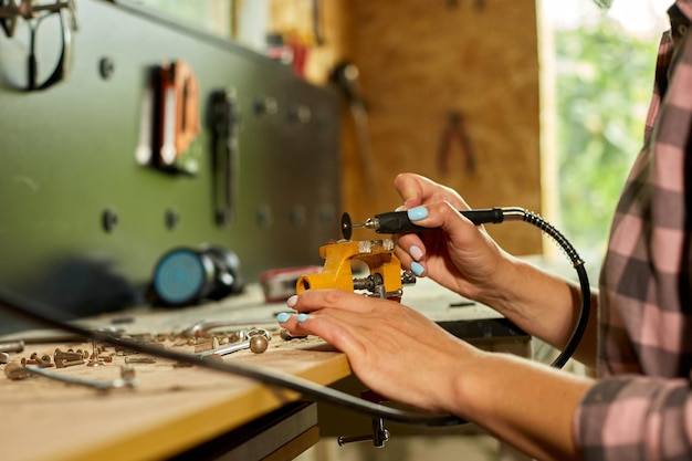 Femme utilisant une machine de broyage électrique femme broyant à la main un métal écrous boulons dans l'atelier étincelles dans le travail du métal