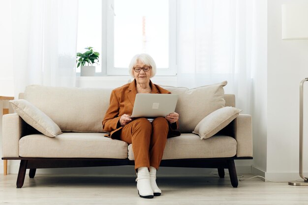 Femme utilisant un ordinateur portable alors qu'elle est assise sur le canapé à la maison