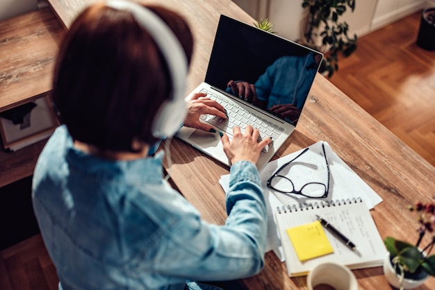 Femme utilisant un ordinateur portable et écoutant de la musique sur un casque