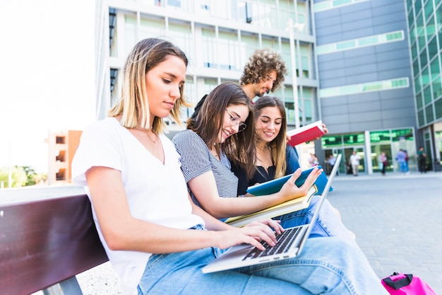 Photo femme utilisant un ordinateur portable pour des études près d'amis