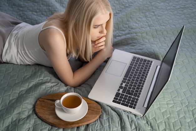 Femme utilisant un ordinateur portable sur son lit.