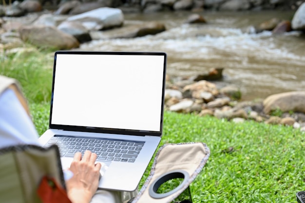 Femme utilisant un ordinateur portable tout en prenant des vacances au camping naturel