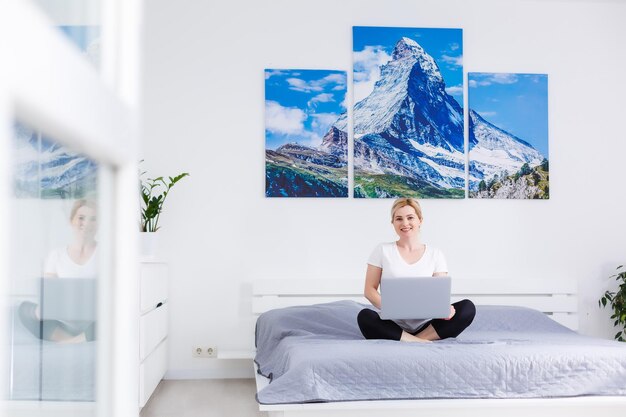 Femme utilisant un ordinateur portable tout en se relaxant sur le canapé