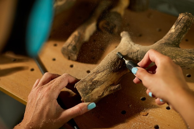 Femme utilisant des outils électriques de travail du bois gravure de sculpture pendant l'artisanat Création de souvenirs artisanaux femme dans un atelier