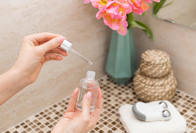 Femme utilisant un sérum de beauté dans la salle de bain