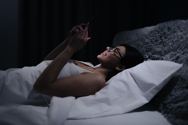 Femme utilisant un smartphone avant de dormir