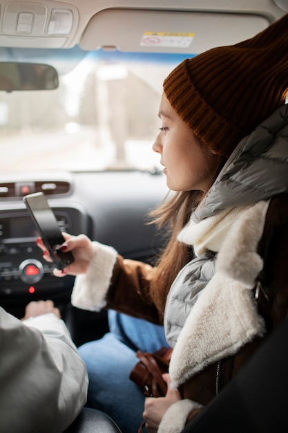 Femme utilisant un smartphone dans la voiture lors d'un voyage en hiver