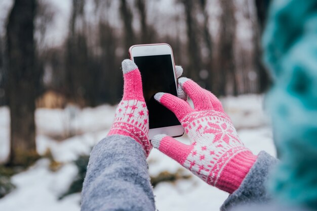 Femme utilisant un smartphone en hiver avec des gants pour écrans tactiles