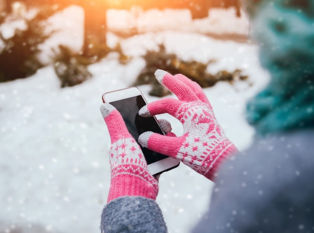 Femme utilisant un smartphone en hiver avec des gants pour écrans tactiles