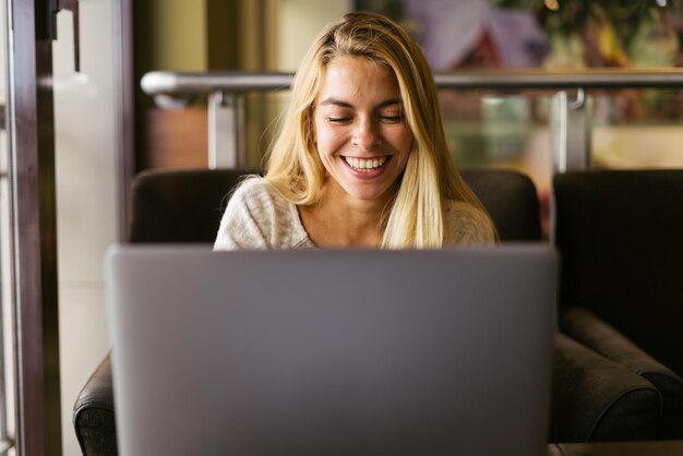 Femme utilisant son ordinateur avec un sourire à pleines dents