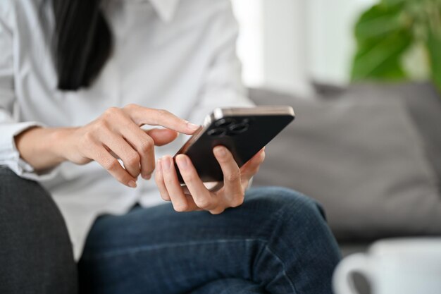 Une femme utilisant son smartphone tapant à l'écran tenant son téléphone portable