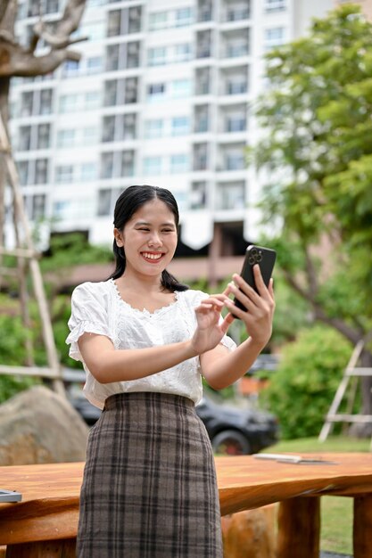 Une femme utilisant son smartphone tout en se relaxant dans le jardin extérieur de sa copropriété