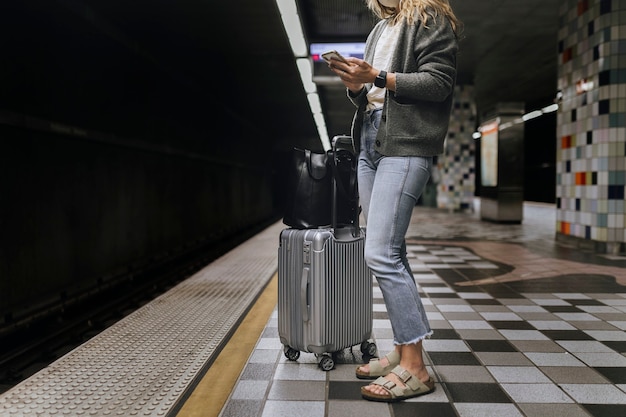 Photo femme utilisant son téléphone portable en attendant le train pendant la pandémie de coronavirus