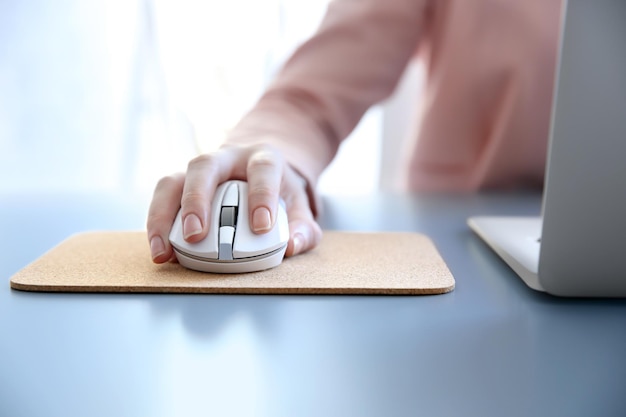 Femme utilisant une souris d'ordinateur avec un ordinateur portable sur la table