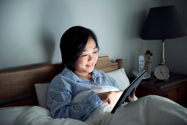 Une femme utilisant une tablette au lit