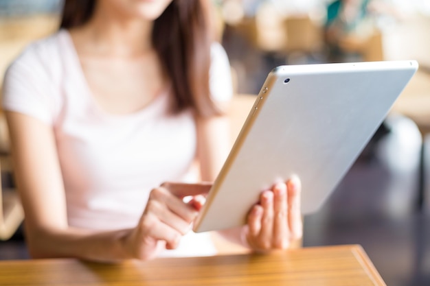 Femme utilisant une tablette numérique au café