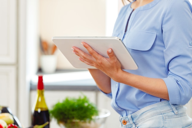 Femme utilisant une tablette numérique pendant la cuisson dans la cuisine