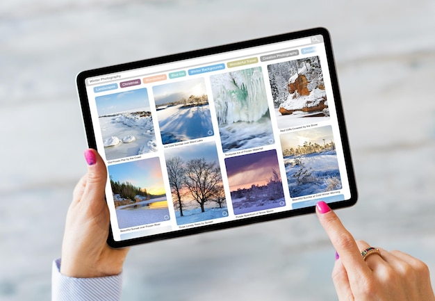 Femme utilisant une tablette et parcourant de belles photos d'hiver en ligne